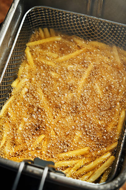 Crispy french fries in a deep fat fryer with steel net basket. French fries