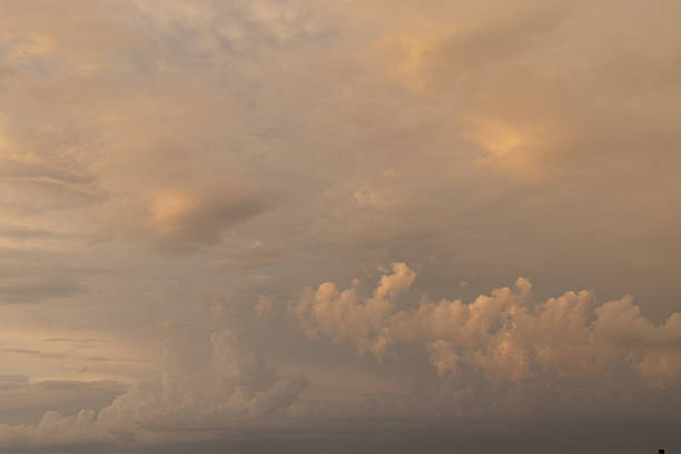 A warm, golden sky fills with soft clouds as evening light casts gentle hues. This tranquil scene conveys calm, balance, contemplation, and serenity, ideal for nature, travel, and ambient backgrounds.