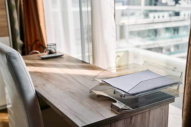 Bright and Modern Workspace Featuring a Sleek Desk with Clear Document Trays, a Cozy Chair, and Panoramic Views through Large Windows.