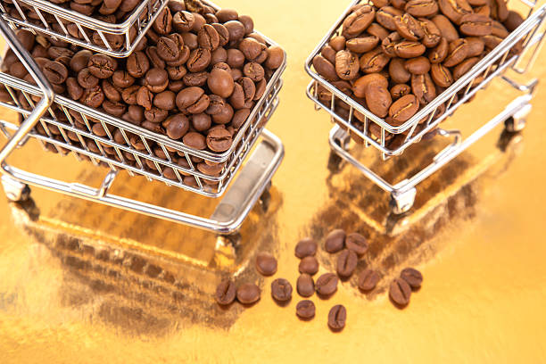 istock Coffee beans stacked in shopping carts on a shiny gold surface during daylight 2248750792