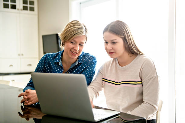 istock A mother using a laptop in kitchen with teenager 2248752018