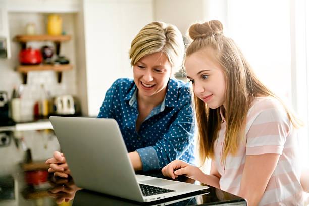 istock A mother using a laptop in kitchen with teenager 2248752020