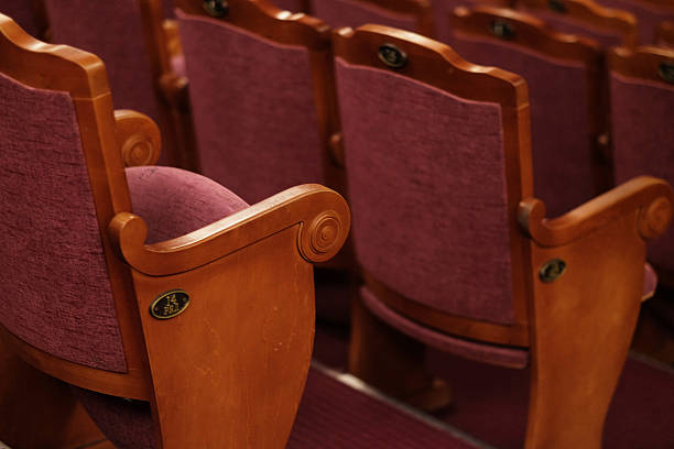 Two vintage red movie theater chairs isolated on a white background
