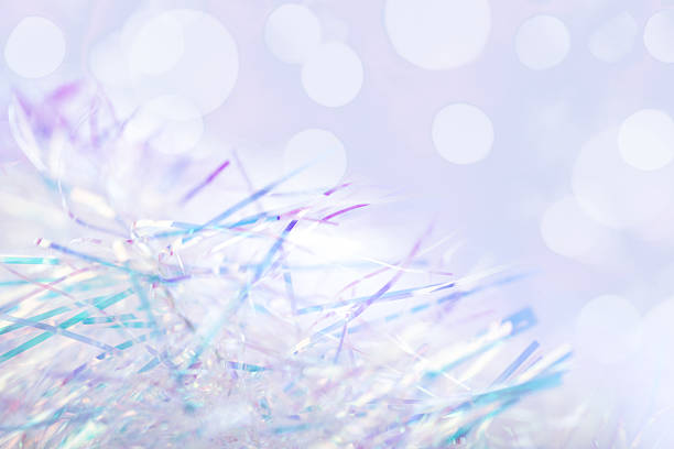 Shimmering tinsel strands close-up. The background features soft, blurred  lights that enhance the festive atmosphere. Nice bokeh, space for copy.