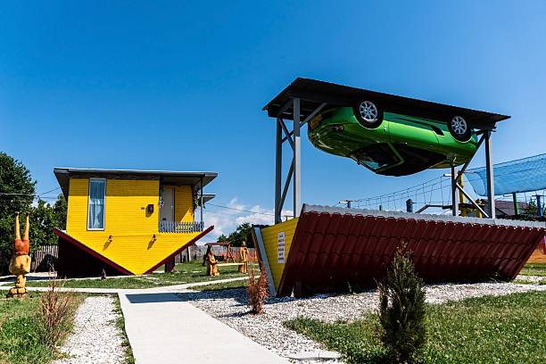 Poienari, Romania – August 04, 2022: Overturned unique Romania house. Overturned car hanging on the top.