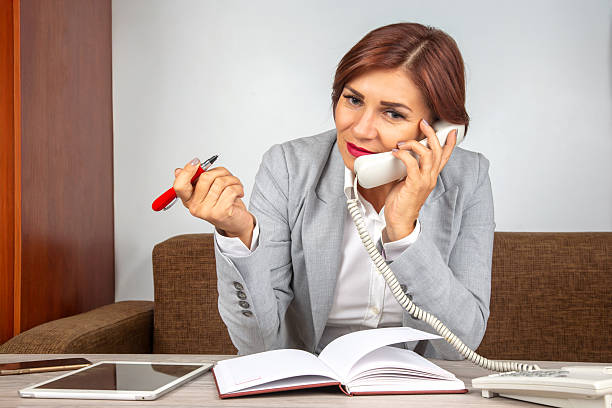istock Businesswoman engages in phone call while taking notes in modern office setting 2248770066