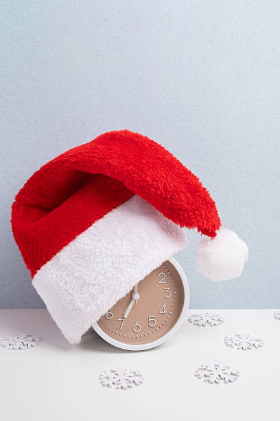 istock Alarm clock covered with santa hat on a green background. Holiday Countdown. 2248770185