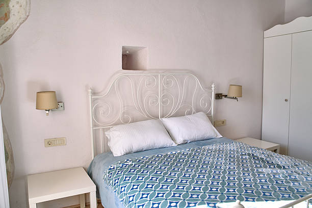 istock A Cozy Bedroom Featuring an Elegant White Bed Frame, Soft Pillows, a Blue Patterned Quilt, and Simple Nightstands Against a Light-Colored Wall 2248770926