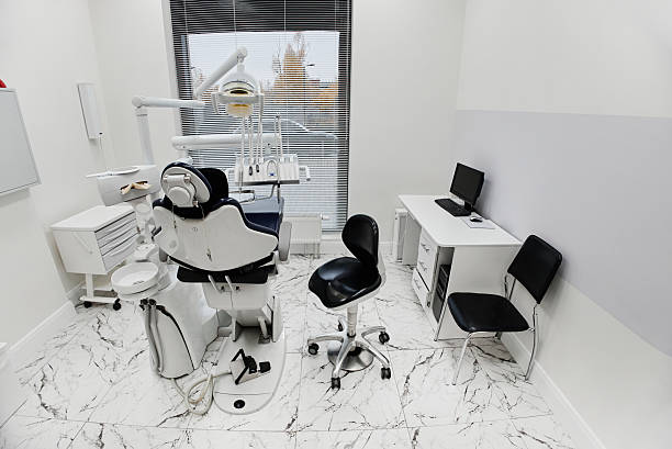 Empty dental office showing modern dental chair, equipment and computer workstation, clean clinical environment prepared for patients attending dental appointments or procedures