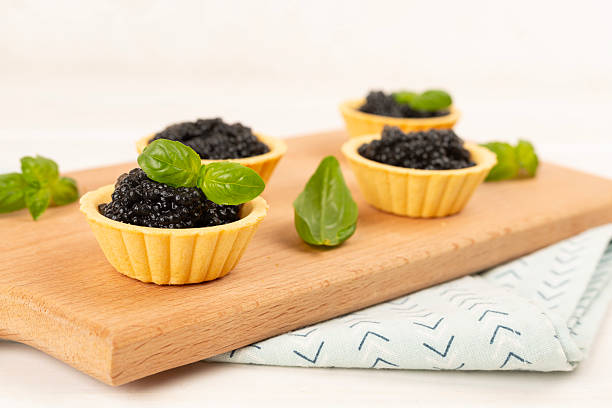 istock Tartlets with black caviar served on on wooden table 2248779657