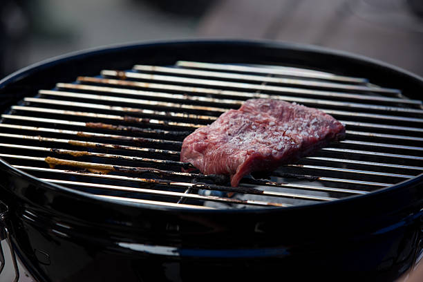 a single piece of raw meat seasoned with salt, freshly placed on the grill