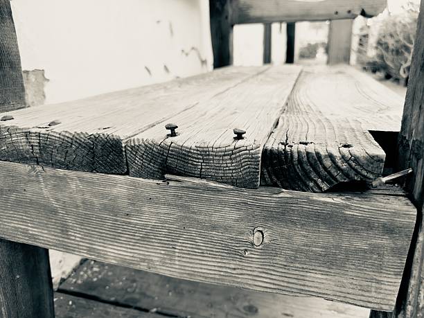 Detailed close-up of the weathered wooden planks of a wagon bed, highlighting the texture and nails. Black and white.