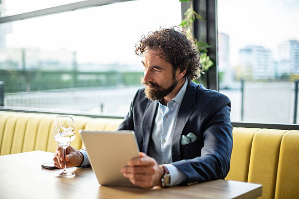 istock Successful businessman working on tablet holding wine glass 2248795020