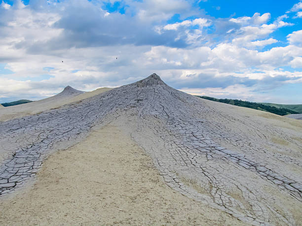 Mud volcano in Romania with cracked barren surface dry clay patterns geological landscape natural texture unique terrain under clear daylight showing rugged shapes earthy tones in active erosion area