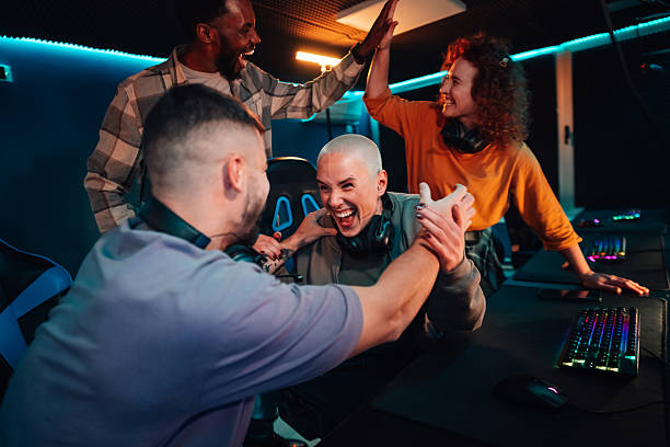 Friends and gamers cheering and high-fiving after winning a video game competition indoors at a gaming cafe