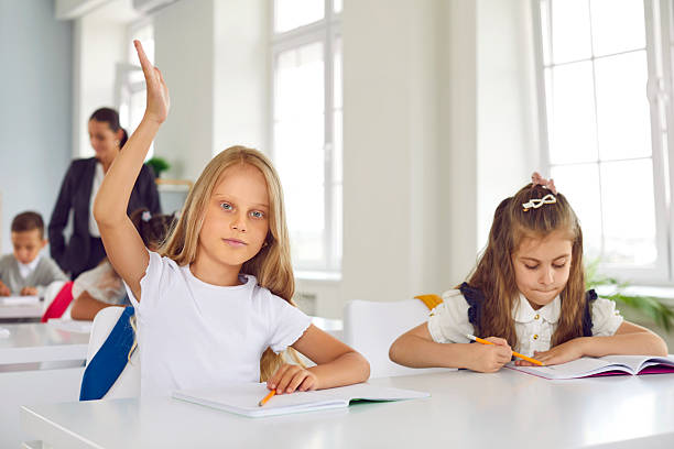 istock Smart little schoolgirl raises her hand during lesson, wanting to answer teacher's question. 2248801052