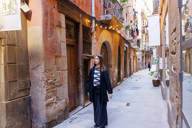 istock Young woman walking in old streets while reading something on her phone and viewing stores 2248804361