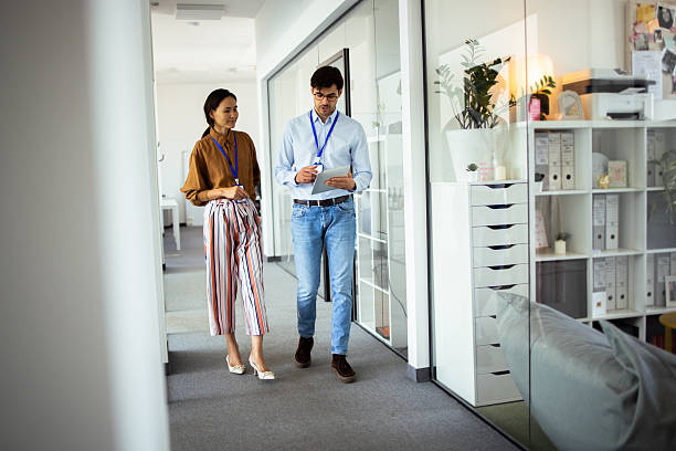 istock Two business colleagues walking and talking in modern office corridor 2248808318