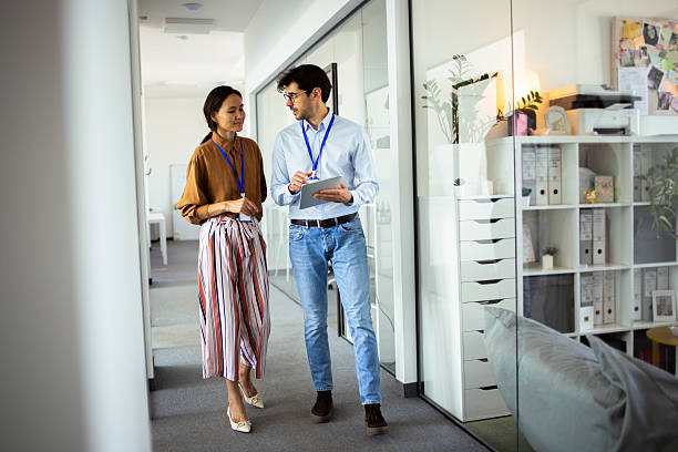 istock Business colleagues walking and talking in modern office corridor 2248808474