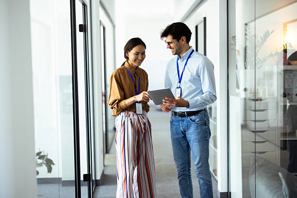 istock Smiling business colleagues using digital tablet in office corridor 2248808545