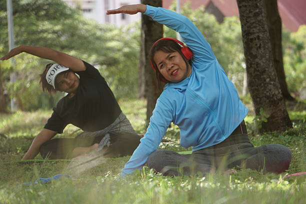 An Asian woman is enjoying outdoor morning workout (using resistance band) near to paddy field.