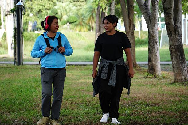 Two friends walking and chatting casually in the park after completing their exercise session.
