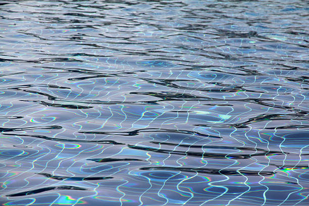 Defocus blurred transparent blue colored clear calm water surface texture with splashes and bubble. Trendy abstract nature background. Water wave in sunlight with copy space. Blue watercolor shining.