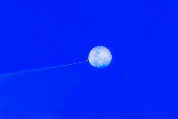 istock An airplane's contrail streaks past the moon 2248813850