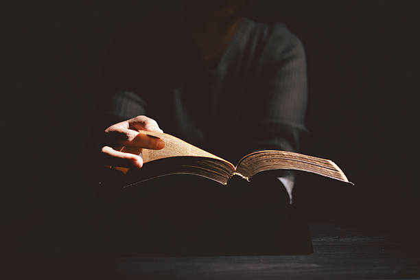 istock Hands holding and offering the Holy Bible with dramatic light in darkness, symbolizing Christianity, faith, gospel truth, worship and hope. Concept of God Word bringing light to life. 2248814632