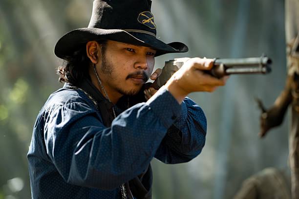 istock A cowboy aiming rifle in a forest camp, with sunlight streaming through the smoke 2248815923