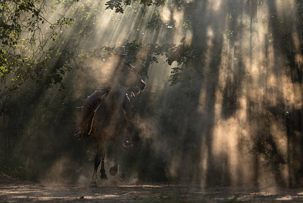 A cowboy riding a horse through dramatic rays of sunlight shining between the trees, creating a cinematic western atmosphere