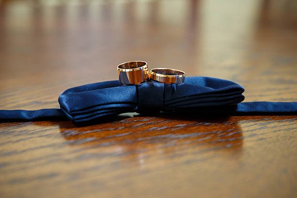 gold wedding rings lie on a man's bow tie