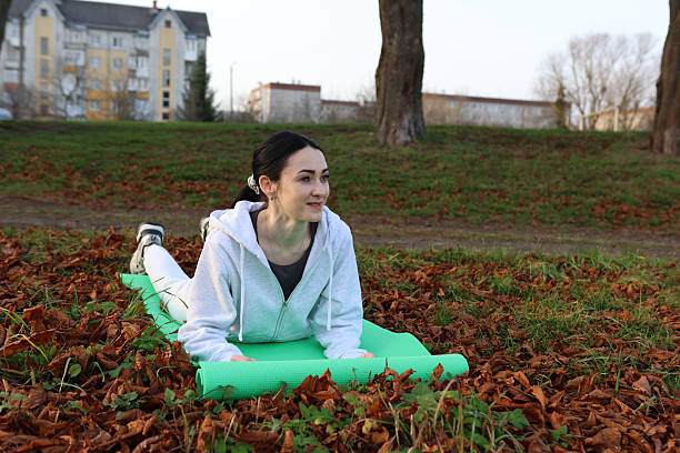 Woman doing morning exercises on a mat outside
