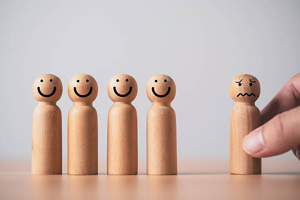 istock Wooden figures with happy faces standing together while one sad figure is being removed symbolizing layoff employee selection rejection workplace stress and human resources decisions 2248822613