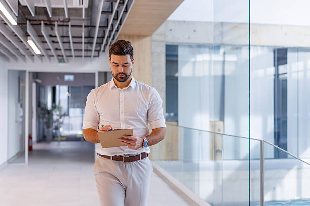 istock Businessman walking and writing on a clipboard in office hallway 2248826914