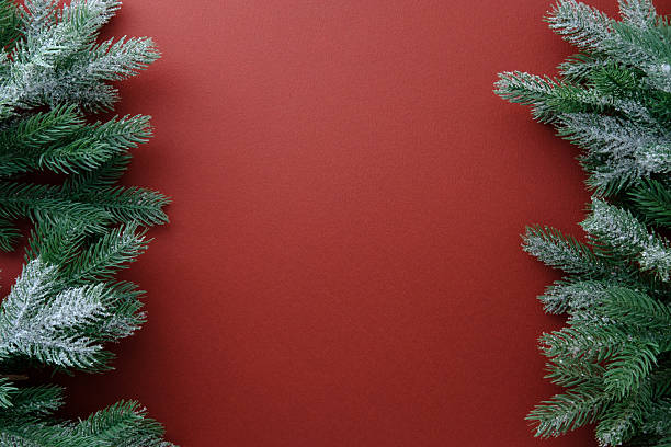 istock Christmas frame of pine branches on rich red background. 2248830092