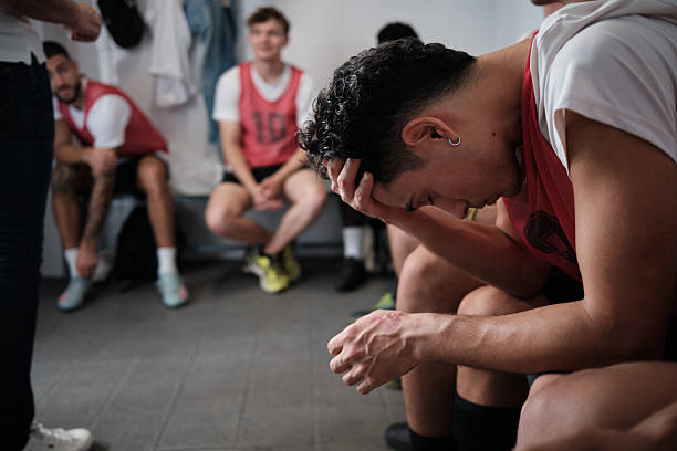 Young male athletes showing disappointment and sadness in a locker room after a game, reflecting on their performance and defeat