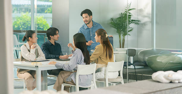 istock A group of five professionals collaborates around a table in a modern office, engaging in discussion and sharing ideas. 2248833087