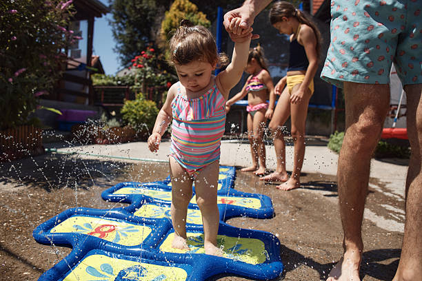 Happy toddler enjoying water play with family on a hot summer day