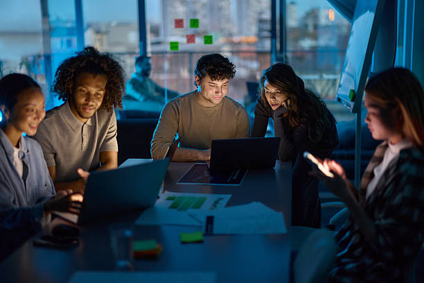 istock Team of creative colleagues working on laptops late in the office. 2248835500