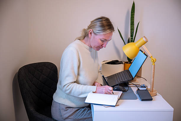 istock Woman writing in notebook while working at home office desk 2248838681