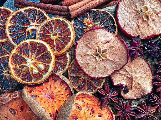 A vibrant overhead shot of dried oranges, apples, cinnamon sticks, star anise, and exotic fruits on a wooden surface. The image captures a cozy, festive atmosphere with rich textures and natural hues. Ideal for holiday content, winter recipes, or seasonal wellness themes. Copy space available for overlay text or editorial use.