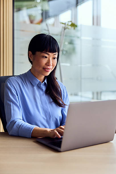 istock Asian Woman Working At Modern Office Desk On Laptop In Bright Open Workspace 2248839007