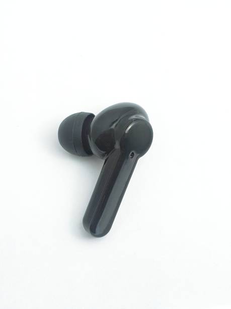 istock a cheap sleek black wireless earbud rests on a clean white surface, presented from a top-down perspective. Its ergonomic design features a comfortable black ear tip and a polished 2248841360