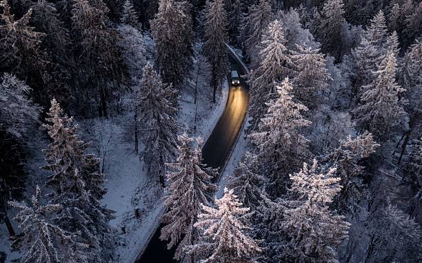 istock Snowy forest with winding road and car. 2248842418