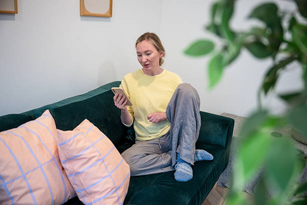 istock Woman relaxing on sofa while using smartphone at home 2248844288