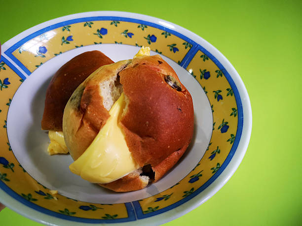 Overhead view of a plate of Hot Cross Buns on a rustic dark wooden table top.