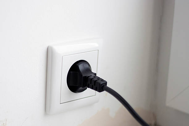 istock Close up of black cable plugged in the socket, white wall 2248847315