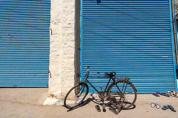 Kallidaikurichi, Tamil Nadu, India - September 23 2023: Old bicycle resting next to closed blue shutters in an urban setting during daylight