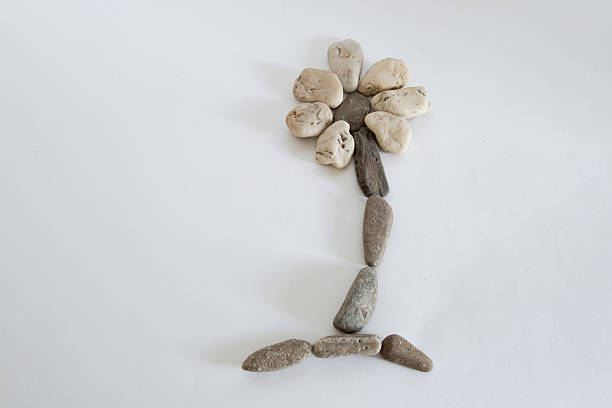 A medium group of river stones in different colour shades are stacked and arranged as a flower